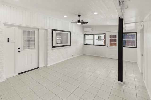 interior space with ceiling fan, light tile patterned flooring, a wall mounted AC, and brick wall