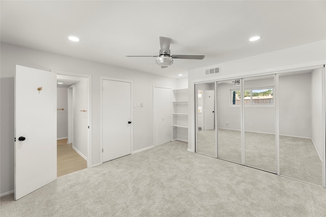 unfurnished bedroom featuring light carpet, ceiling fan, and multiple closets