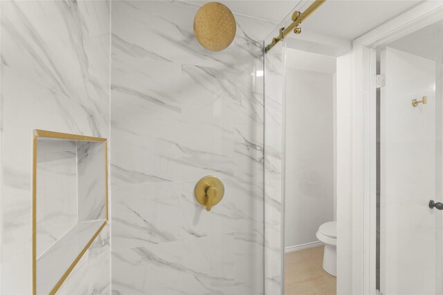 bathroom featuring a tile shower and toilet