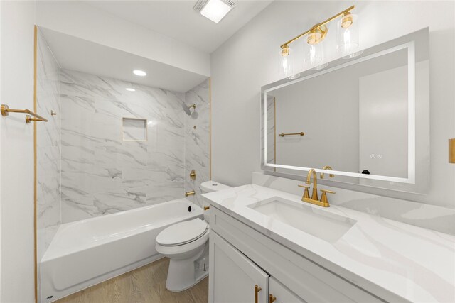 full bathroom featuring vanity, tiled shower / bath combo, toilet, and hardwood / wood-style flooring