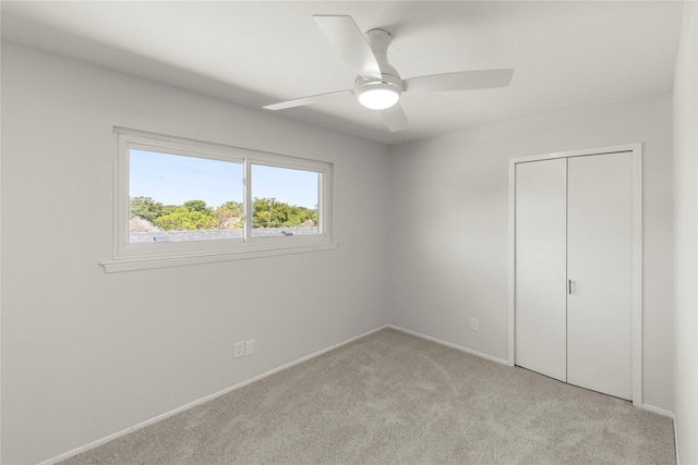 unfurnished bedroom with light colored carpet, ceiling fan, and a closet