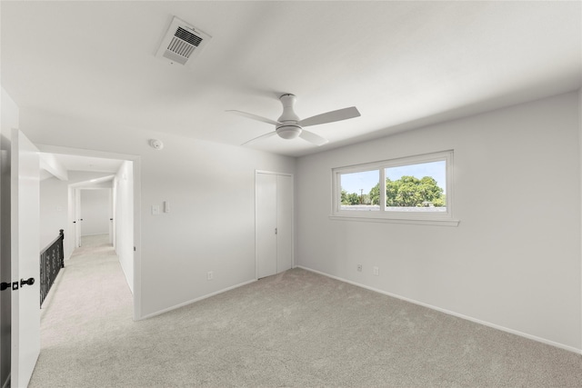 unfurnished bedroom with ceiling fan, light colored carpet, and a closet