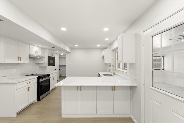 kitchen featuring electric range oven, black microwave, sink, white cabinets, and kitchen peninsula