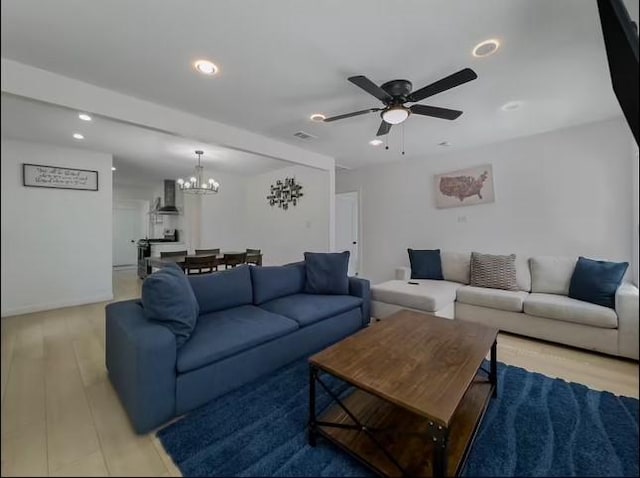 living room featuring light hardwood / wood-style floors and ceiling fan with notable chandelier