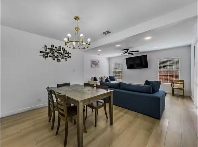 dining area with ceiling fan with notable chandelier and light hardwood / wood-style floors