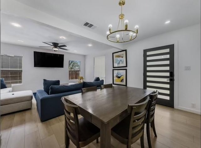 dining space with ceiling fan with notable chandelier and light hardwood / wood-style floors