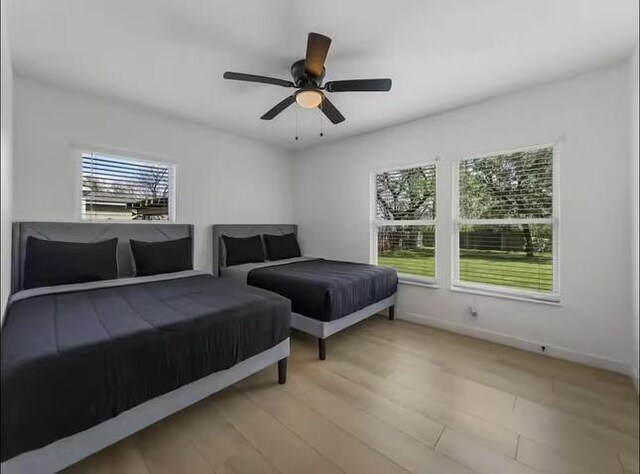 bedroom featuring ceiling fan, light hardwood / wood-style floors, and multiple windows