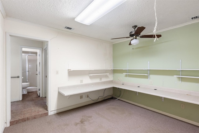 unfurnished office featuring light carpet, a textured ceiling, ceiling fan, and ornamental molding