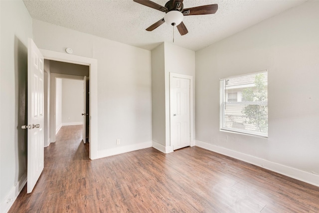 unfurnished bedroom featuring a textured ceiling, ceiling fan, and dark wood-type flooring