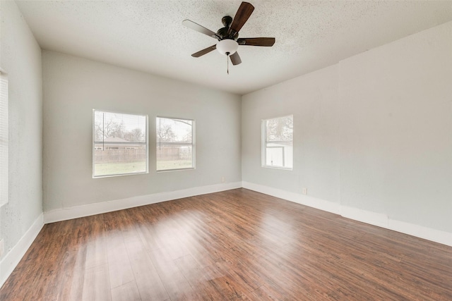 unfurnished room featuring a wealth of natural light, dark hardwood / wood-style flooring, ceiling fan, and a textured ceiling