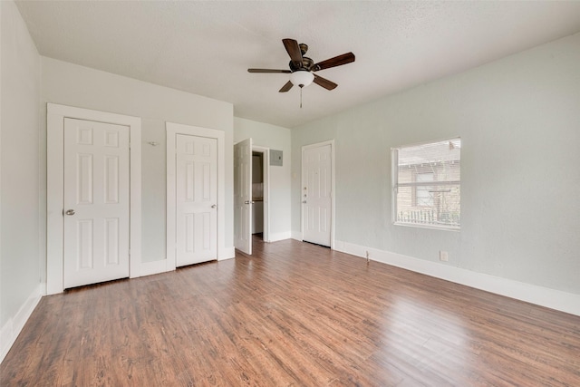 unfurnished bedroom featuring a textured ceiling, two closets, ceiling fan, and dark hardwood / wood-style floors