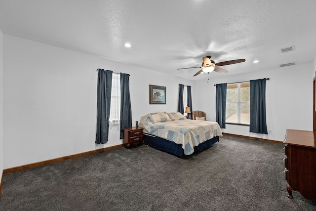 bedroom featuring ceiling fan, dark carpet, and a textured ceiling