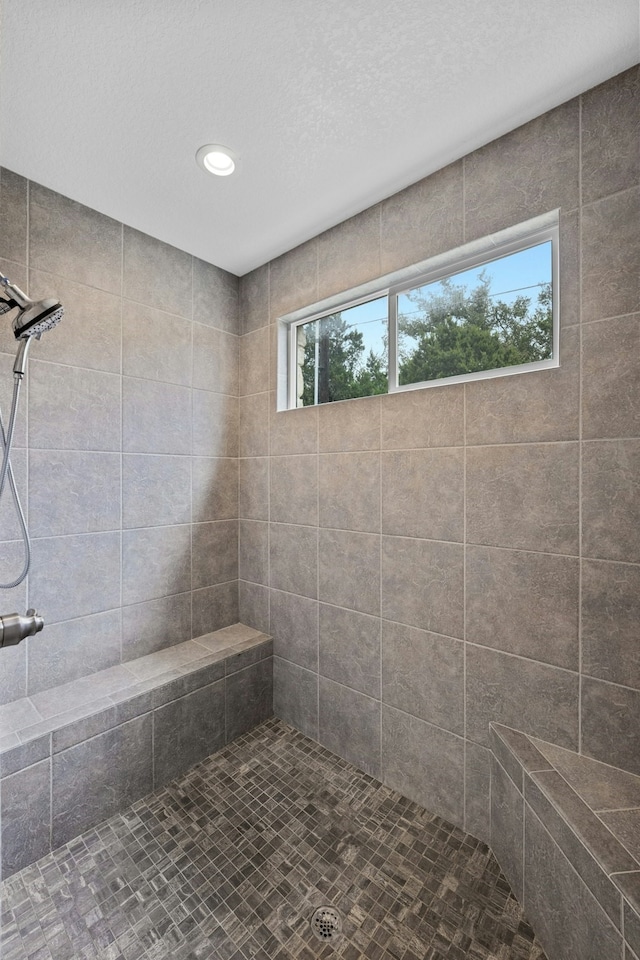 bathroom with a textured ceiling and a tile shower