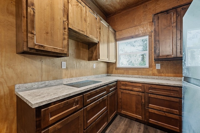 kitchen with light stone countertops, white fridge, black electric stovetop, and dark hardwood / wood-style flooring