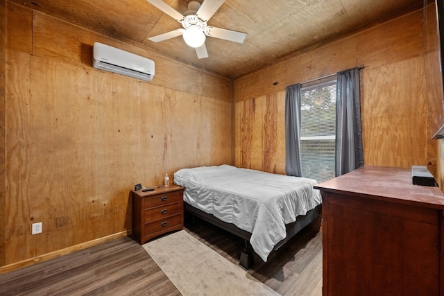 bedroom featuring hardwood / wood-style flooring, a wall mounted air conditioner, ceiling fan, and wood walls