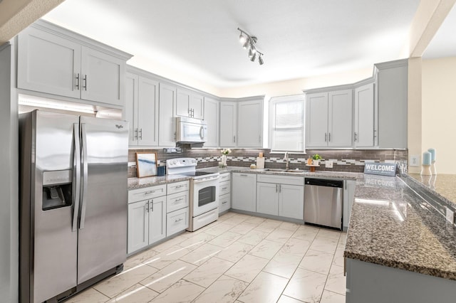 kitchen featuring backsplash, appliances with stainless steel finishes, sink, and dark stone countertops