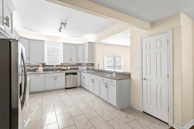 kitchen featuring sink, stone counters, appliances with stainless steel finishes, white cabinets, and backsplash