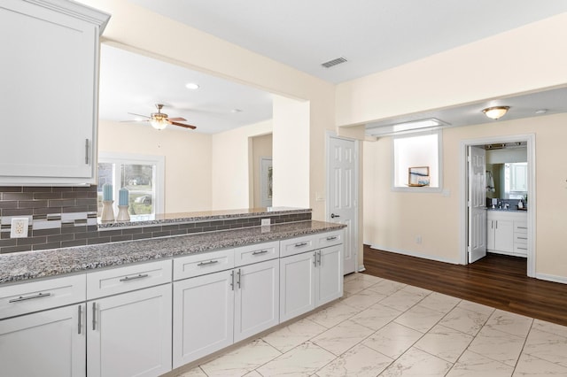 kitchen featuring stone counters, ceiling fan, tasteful backsplash, and white cabinets