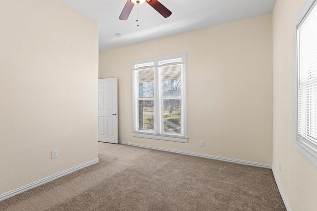 unfurnished room with ceiling fan, light colored carpet, and a wealth of natural light