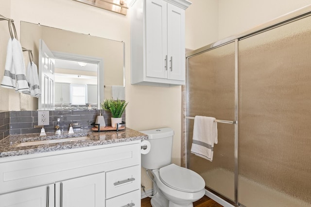 bathroom with vanity, toilet, an enclosed shower, and tasteful backsplash