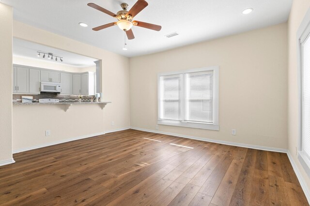 unfurnished living room with ceiling fan and dark wood-type flooring