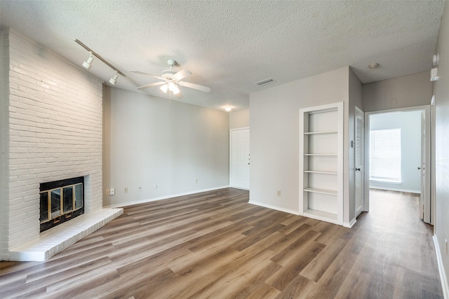 unfurnished living room with a brick fireplace, hardwood / wood-style floors, and a textured ceiling