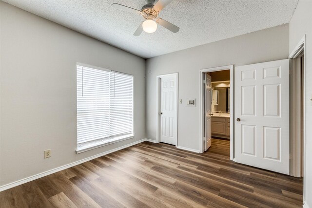 unfurnished bedroom with sink, ceiling fan, connected bathroom, a textured ceiling, and dark hardwood / wood-style flooring