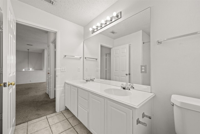 bathroom with tile patterned floors, vanity, toilet, and a textured ceiling