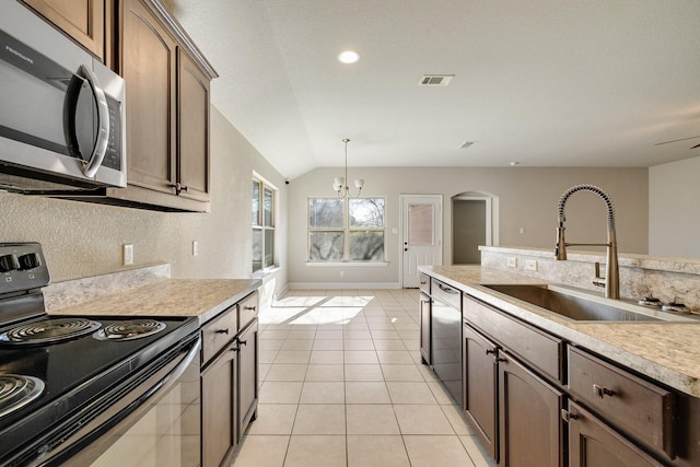 kitchen featuring appliances with stainless steel finishes, light tile patterned floors, sink, decorative light fixtures, and lofted ceiling