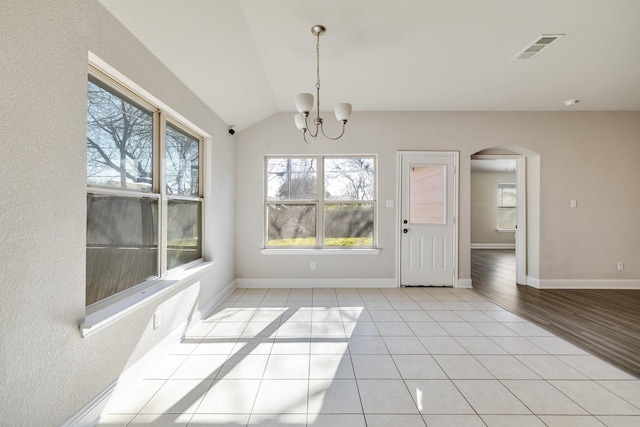 unfurnished dining area featuring vaulted ceiling, light tile patterned floors, and a chandelier