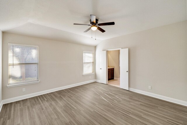 empty room with lofted ceiling, light wood-type flooring, and ceiling fan