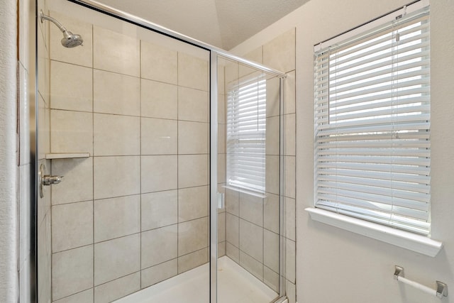 bathroom featuring a textured ceiling and a shower with shower door