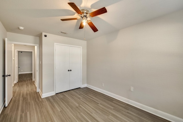 unfurnished bedroom featuring wood-type flooring, a closet, and ceiling fan