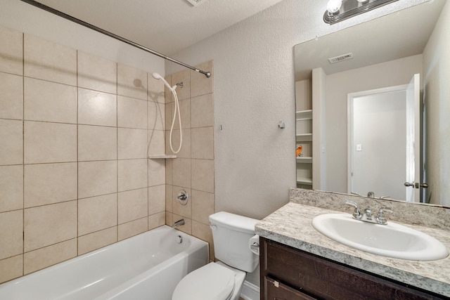 full bathroom featuring a textured ceiling, vanity, tiled shower / bath combo, and toilet