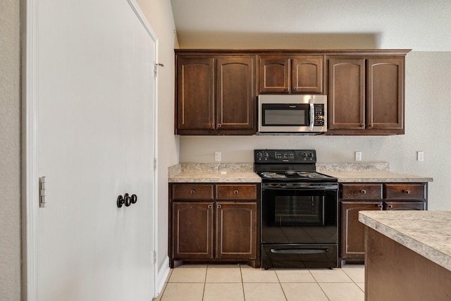 kitchen with light tile patterned floors, black range with electric cooktop, and dark brown cabinetry