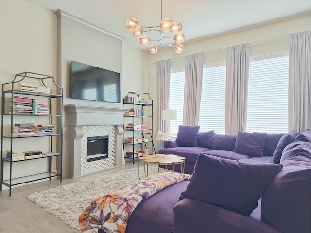 living room featuring a tile fireplace, light hardwood / wood-style flooring, and a notable chandelier