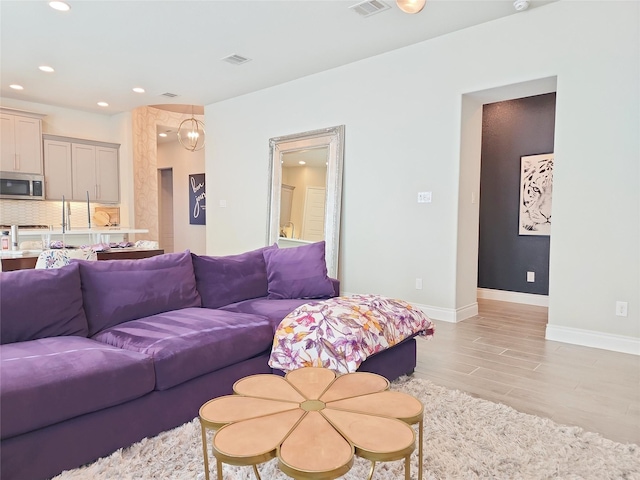 living room featuring light wood-type flooring and a notable chandelier