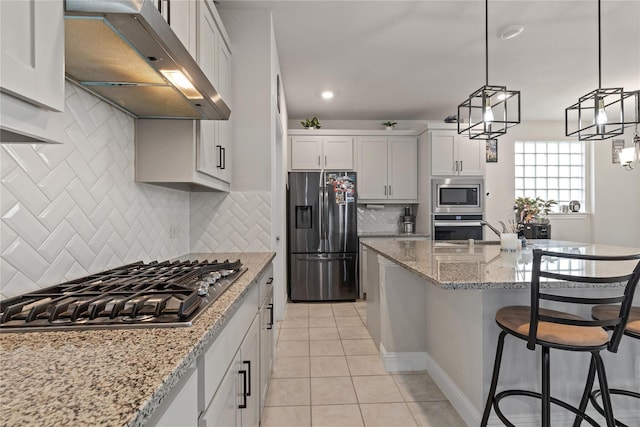 kitchen featuring light tile patterned flooring, appliances with stainless steel finishes, white cabinets, exhaust hood, and light stone counters