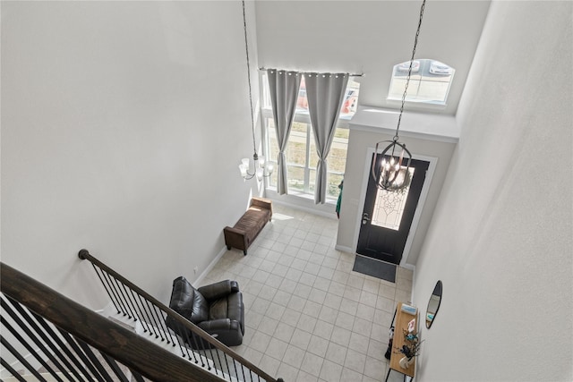 tiled entryway with a chandelier and a towering ceiling