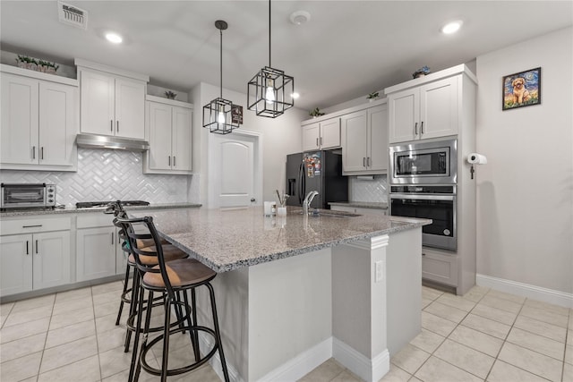 kitchen with a kitchen island with sink, white cabinets, stainless steel appliances, and light tile patterned floors