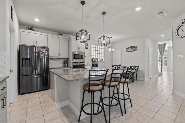 kitchen with appliances with stainless steel finishes, tasteful backsplash, dark stone counters, white cabinets, and a kitchen island