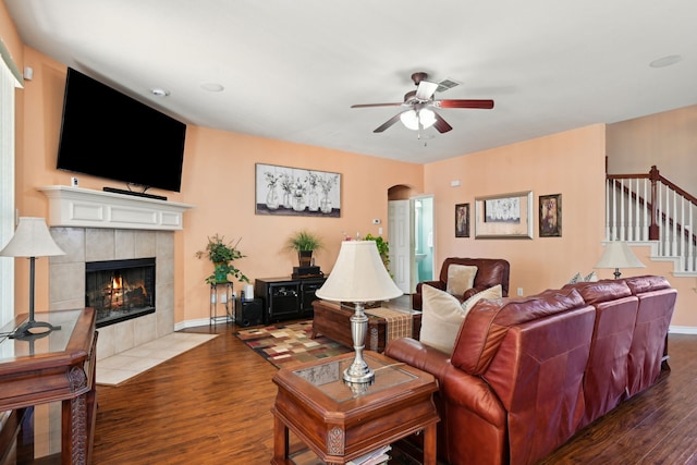 living room with a tile fireplace, hardwood / wood-style floors, and ceiling fan