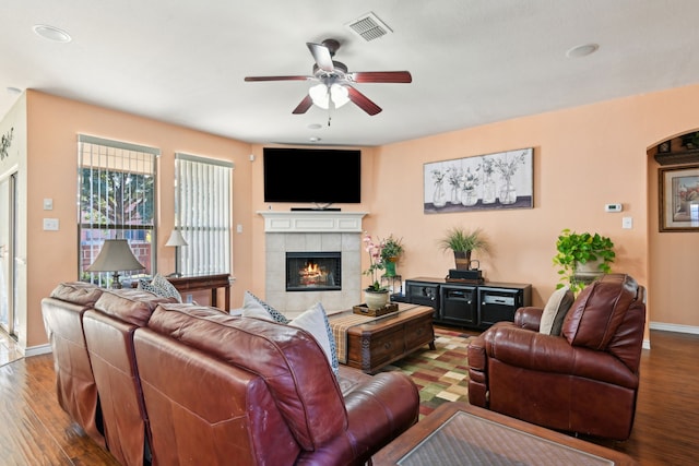 living room featuring hardwood / wood-style flooring, a tile fireplace, and ceiling fan