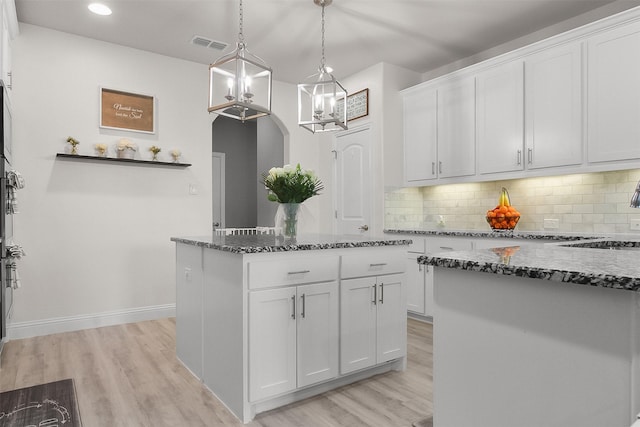 kitchen with hanging light fixtures, dark stone countertops, white cabinetry, and a kitchen island