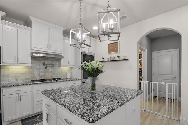 kitchen featuring decorative backsplash, white cabinets, black gas stovetop, and a kitchen island