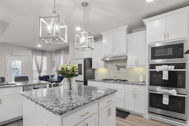 kitchen featuring stainless steel appliances, backsplash, white cabinetry, and a center island