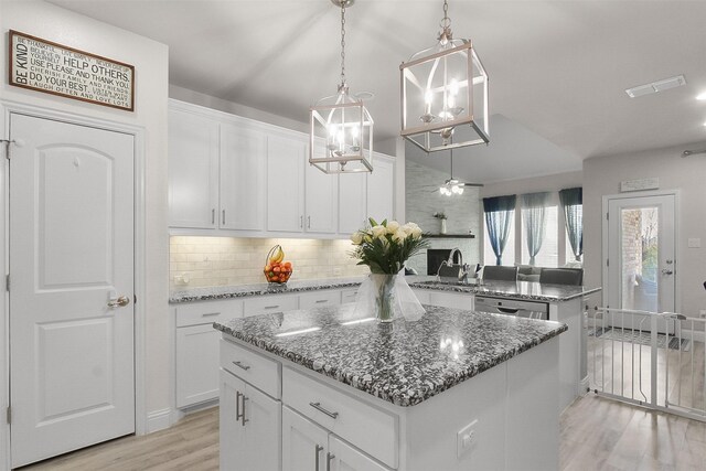 kitchen with ceiling fan, a kitchen island, white cabinets, and hanging light fixtures