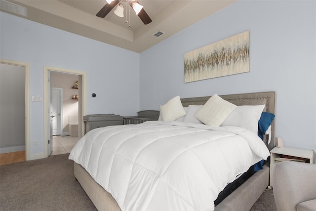 carpeted bedroom featuring ceiling fan and a tray ceiling