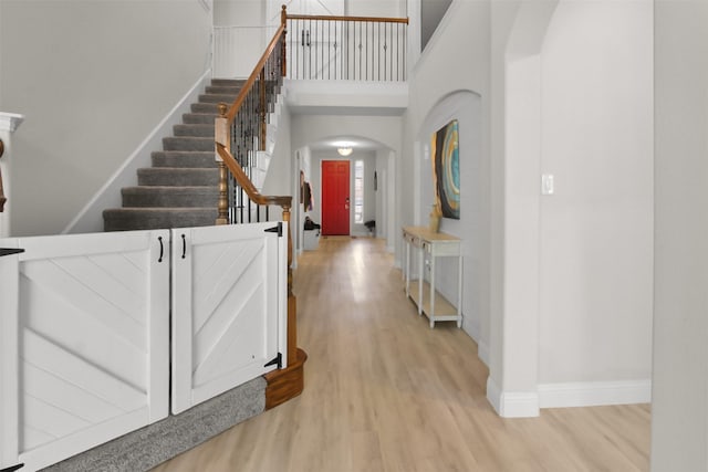 entryway with light hardwood / wood-style floors and a towering ceiling