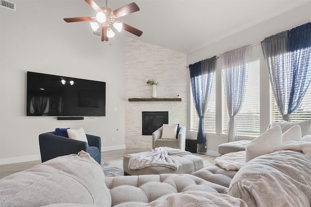 living room with ceiling fan, plenty of natural light, light hardwood / wood-style flooring, and a stone fireplace